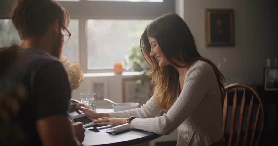 Man and woman sitting at the table talking and laughing while looking at some printed pictures