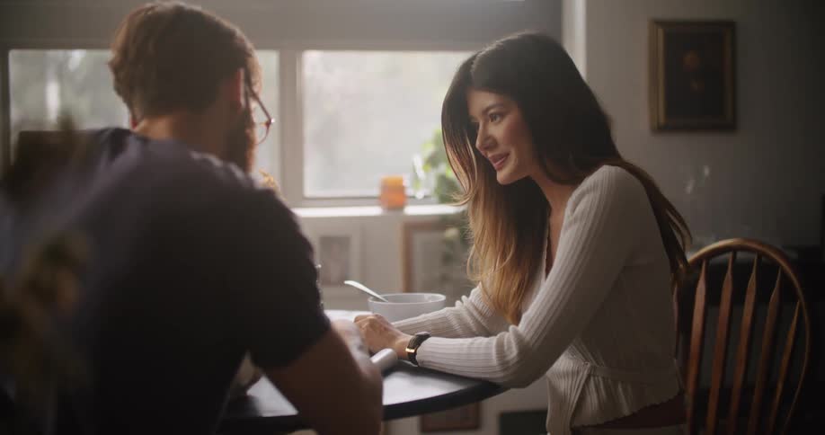 A man and woman sit at a table at home and talk