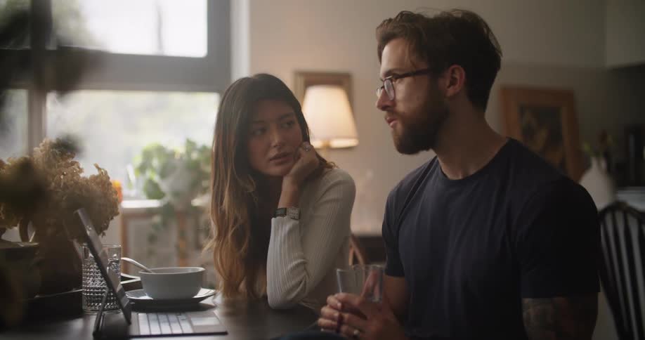 A man and woman sit at their table and talk and point as they look at a laptop