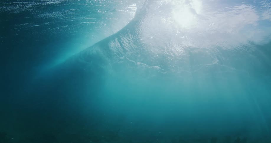 A wave crashes on the surface of the ocean above the sea floor