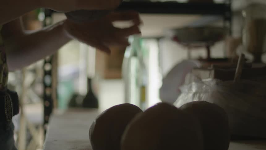 A woman shaping clay into balls and setting them on a table