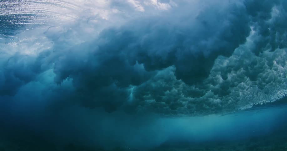 A powerful wave rolls overhead as seen from underneath the surface of the ocean