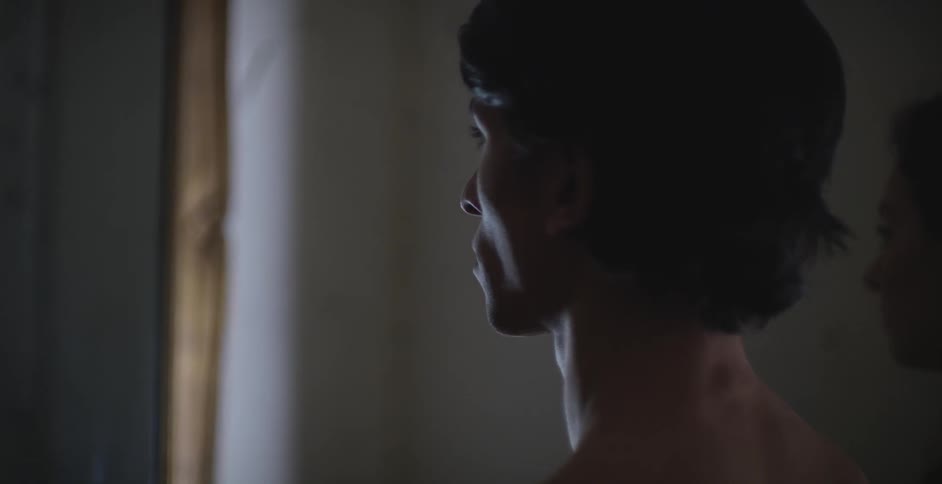 Shirtless man staring forward indoors