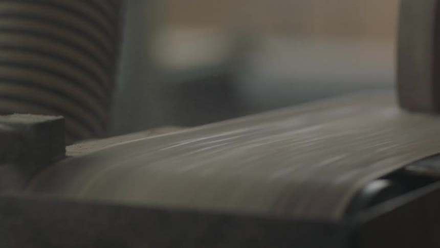 Wood is being run on a sanding belt
