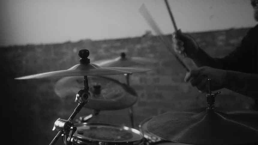 Male drummer plays drums in room