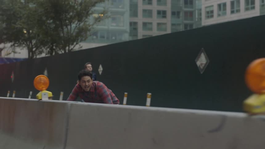 Man skateboarding on a city street next to construction barriers