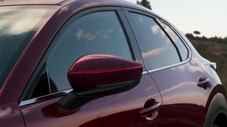 The shiny exterior of a car reflects the clouds moving in the sky above