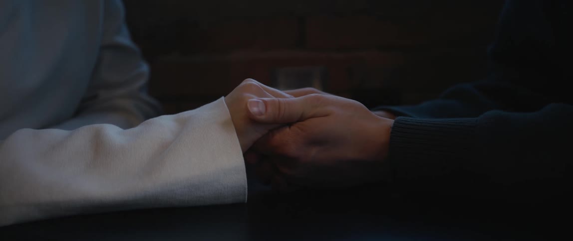 A man caresses a womans hand as they hold hands