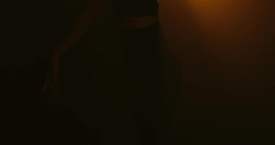 A woman dances under a bright spotlight