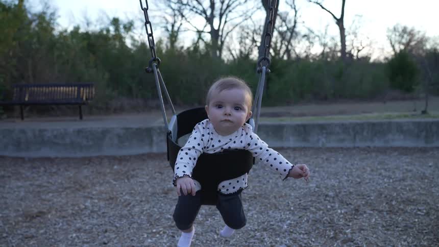 Child swings back and forth reaching toward the adult at the front