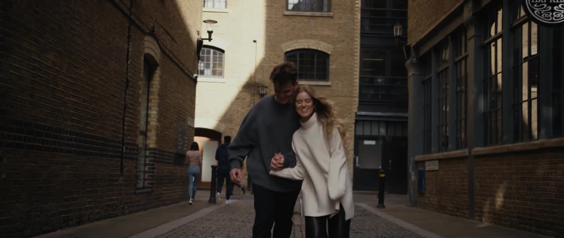 Couple moves down cobblestone street running and smiling while holding hands