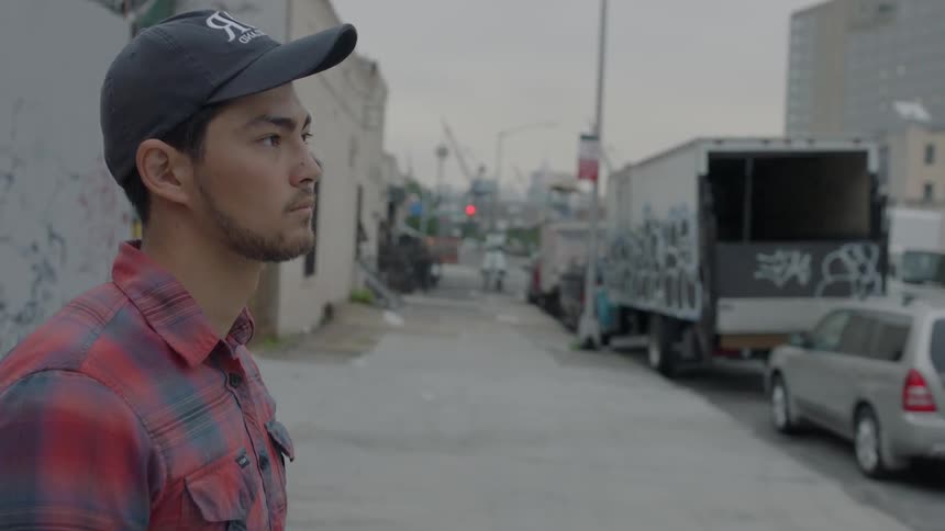 Man standing on a city street wearing a baseball cap