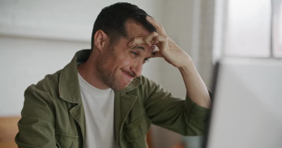 A man attempts to focus himself while using a computer indoors during the day