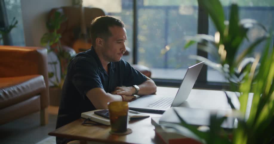 Tired man sitting at the desk using his laptop and smartphone