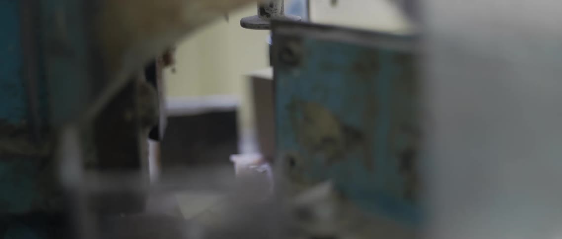 A large blade cuts through a stack of papers in a factory