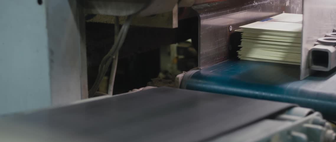 The conveyor belt is moving the stacks of folders