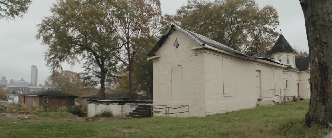 Church building with steeple and backyard with city skyline in the background