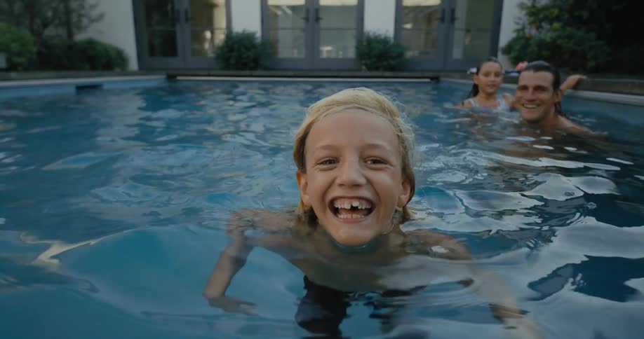 Father smiles as he and daughter watch his son swim