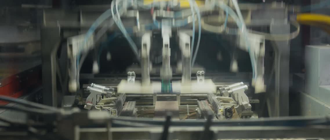 A claw style machine picks up stacks of paper in a factory