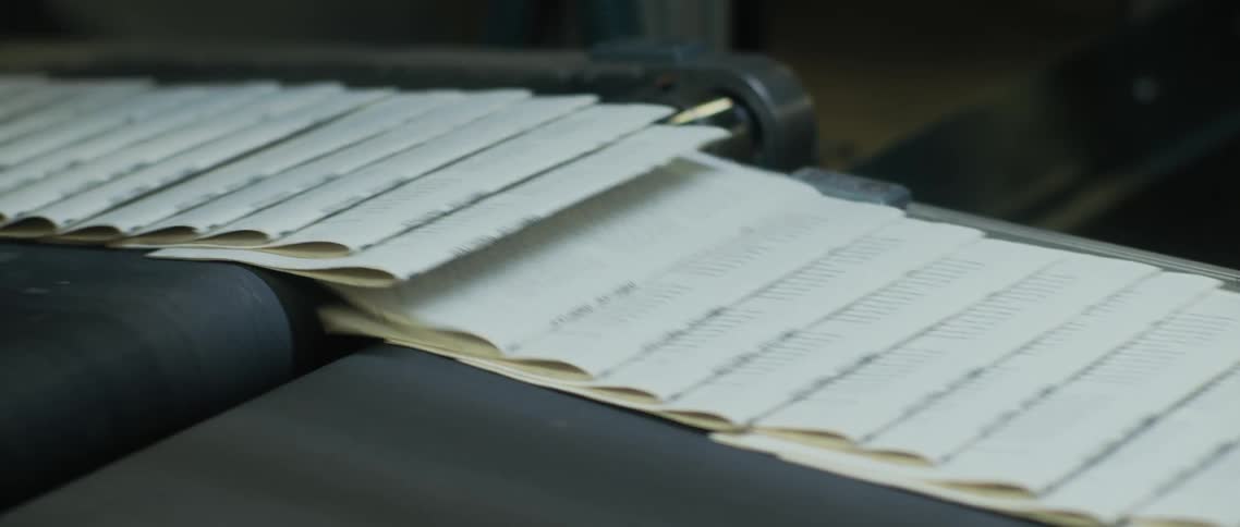 Newspapers roll down a conveyor belt
