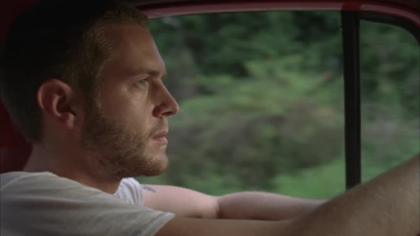A man is driving as wind blows in the window