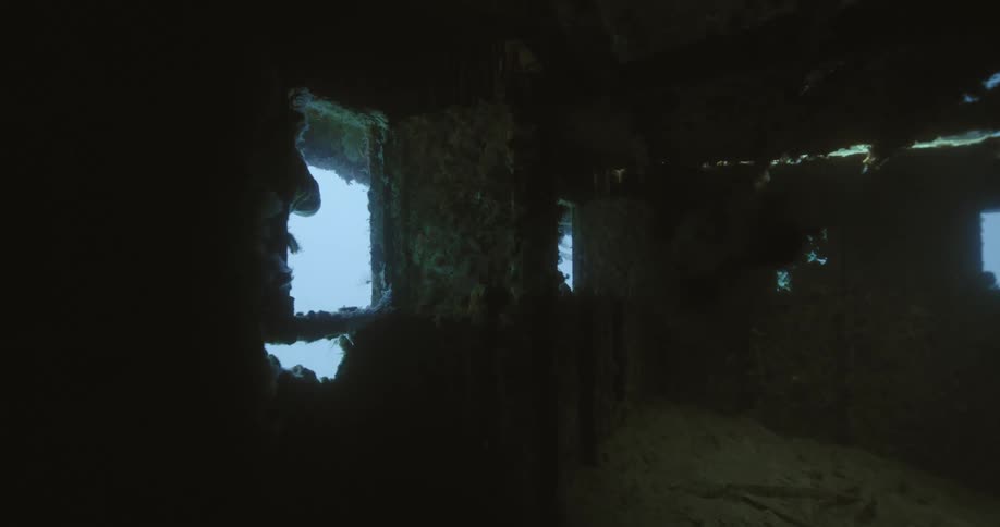 Debris floating inside a cabin of a sunken ship in the blue ocean water