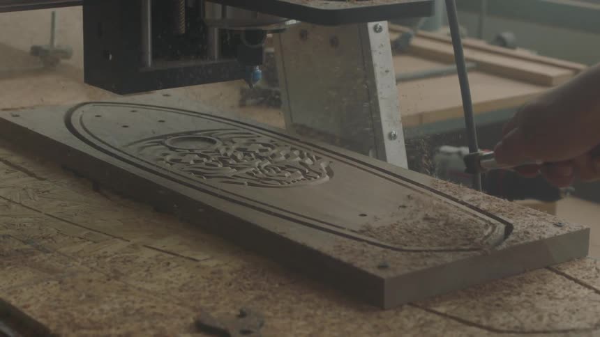 A man blows saw dust off a wooden board