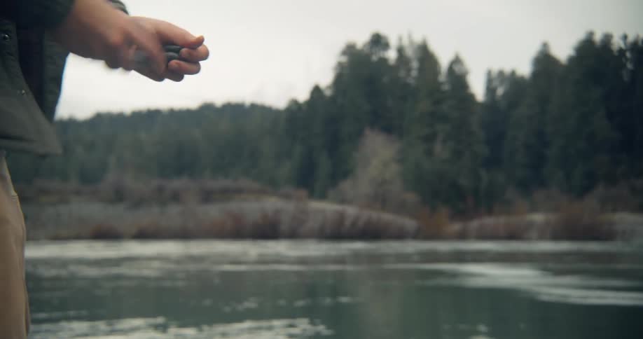 Man throwing flat rocks in the river to practice stone skipping