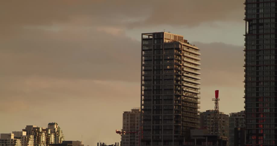 Sunlight shines on tall buildings under a cloudy sky