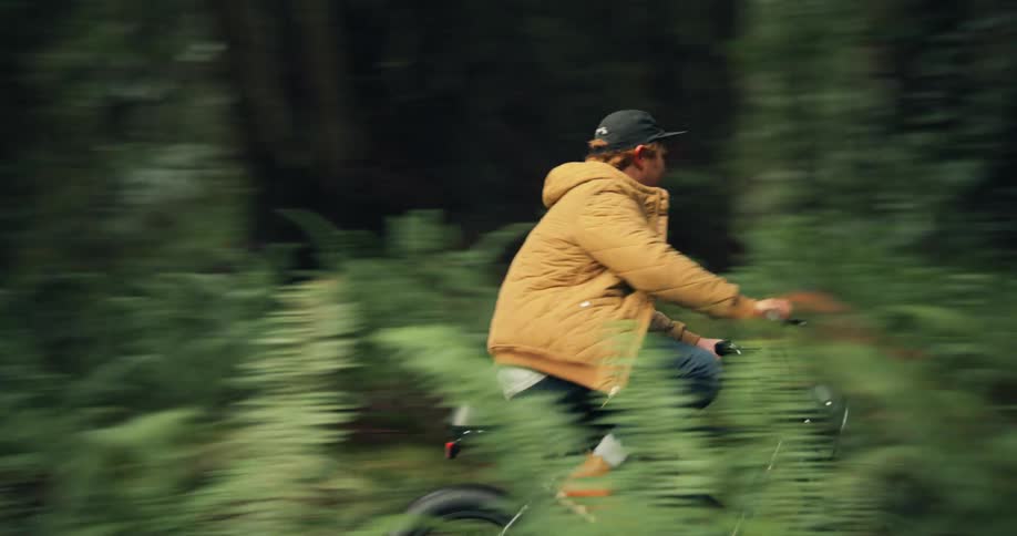 Two men ride their bikes on a trail in a forest