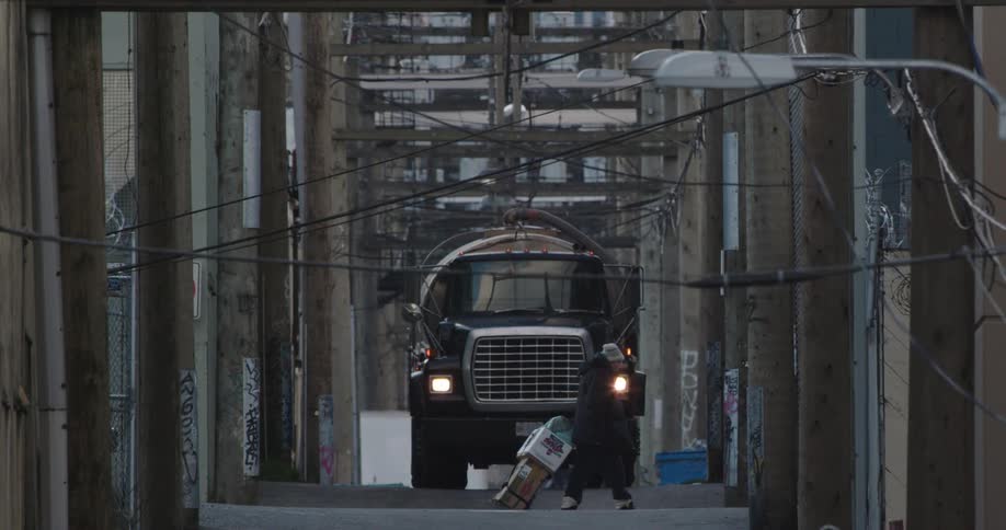 A person crosses the alley in front of a large truck