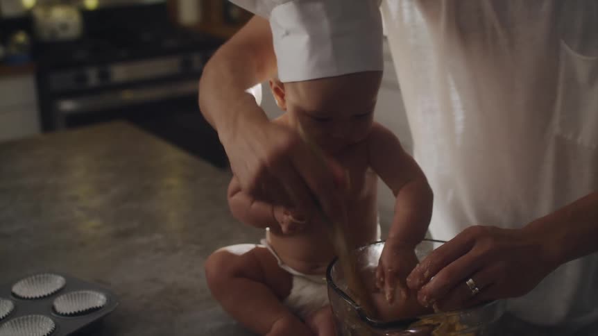 A man has his baby help mix muffin batter
