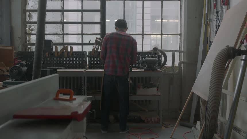 A man walks into a studio over to a workbench