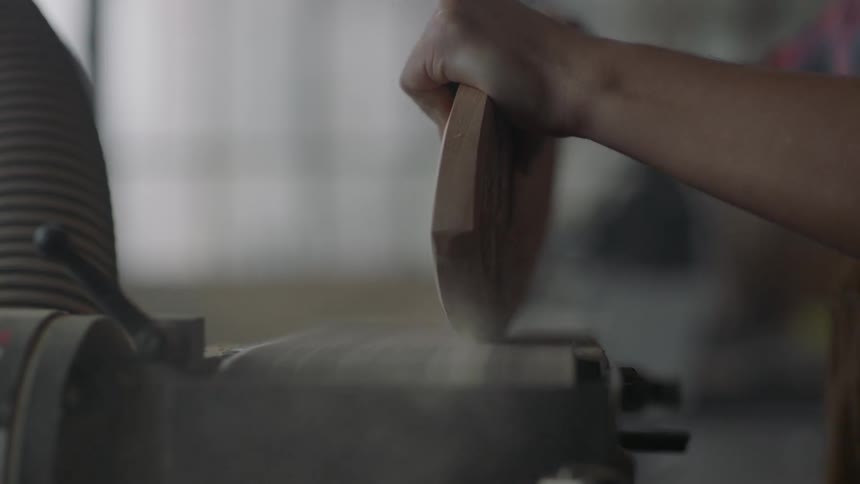 A piece of wood is sanded on a sanding belt