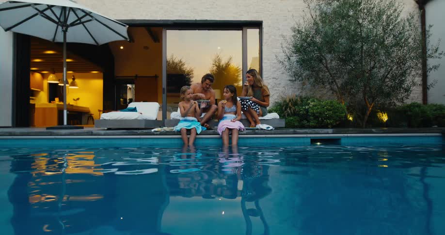 Family sitting poolside eating dinner during sunset