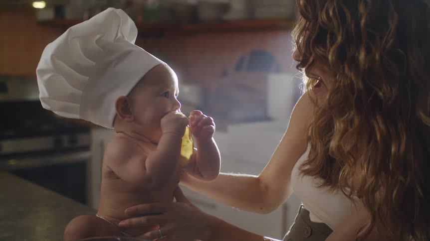 A woman holds her baby as it eats on the kitchen counter
