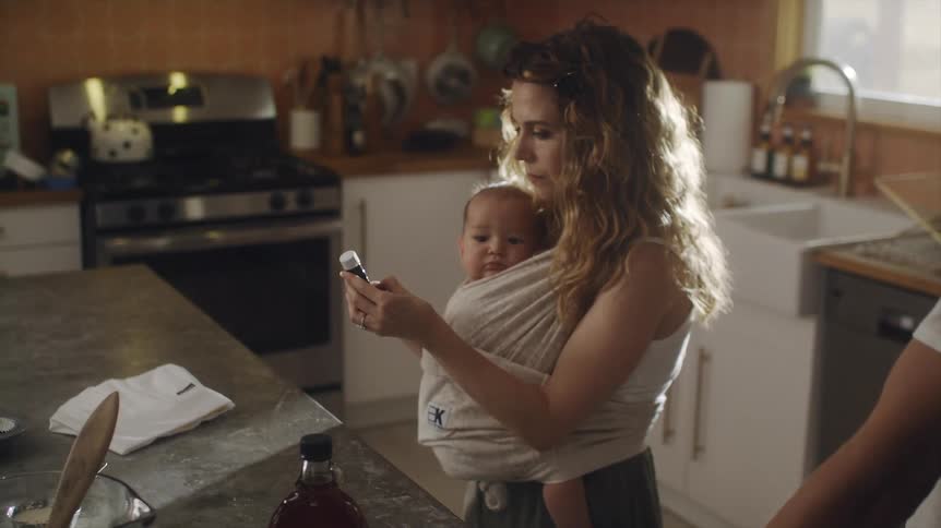 A woman carries her baby in a sling while cooking with her husband