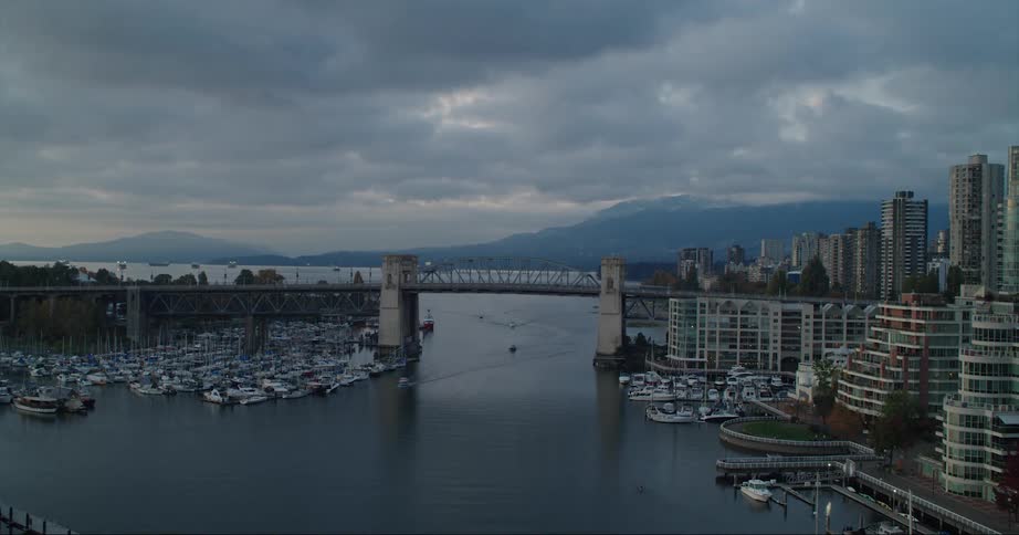 Boats traveling in the false creek harbor and under the bridge in vancouver