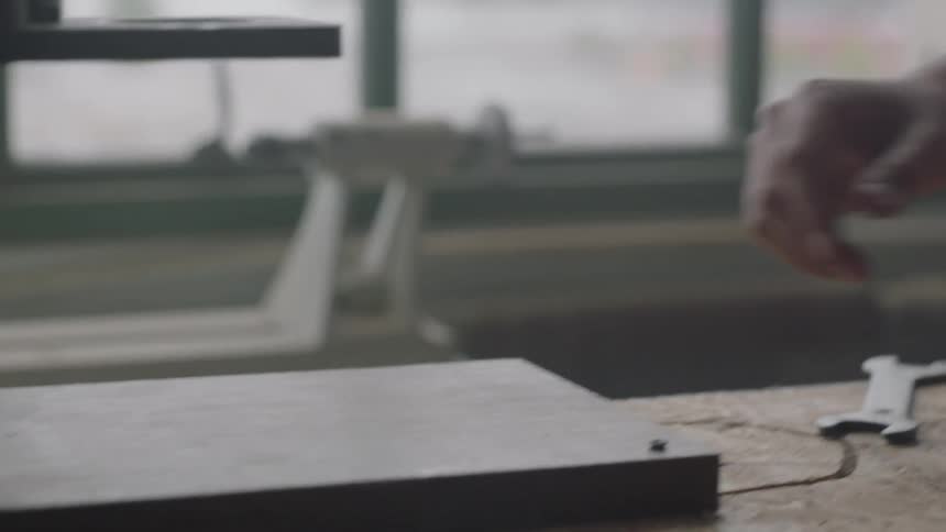 A man wipes off a board on a bench