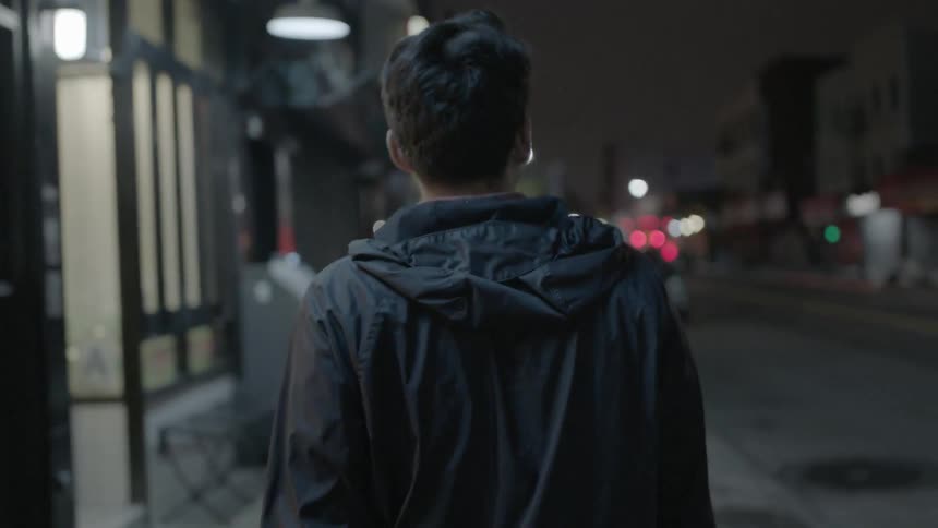 A man walks down a city sidewalk at night