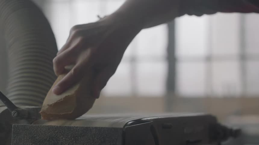 Person using a belt sander to smooth some edges