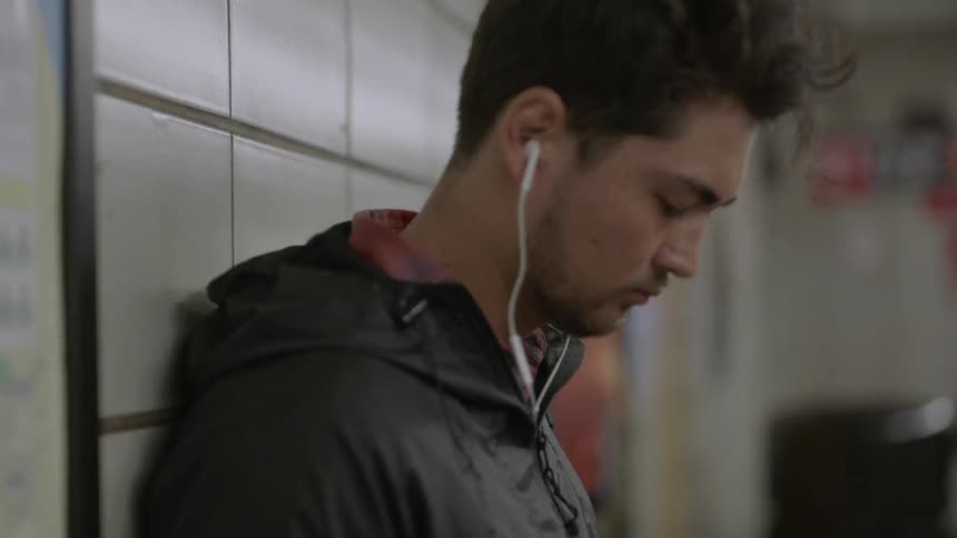 Person leaning against a subway station wall