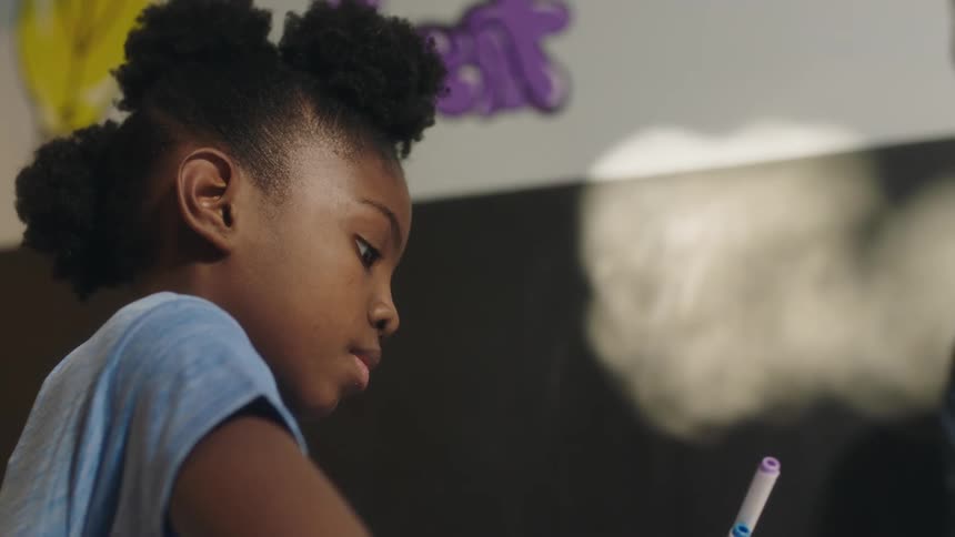 A girl does her schoolwork in a classroom during the day