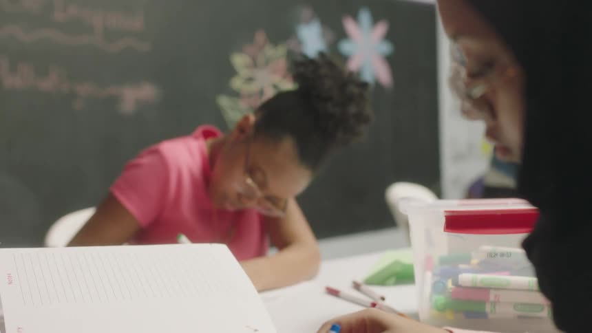 Students do their schoolwork while sitting at a table in the classroom