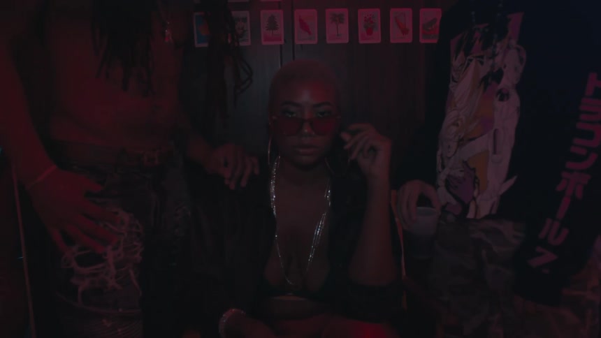 A woman sits on a bench between two men in a dark club