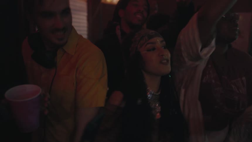 Middle eastern men and women hold their cellphones up with the flashlights turned on as they dance at a nightclub