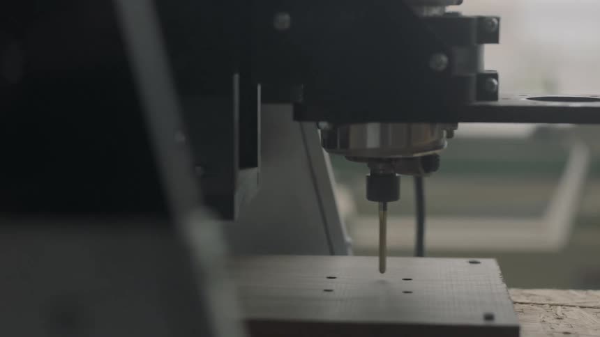 Machine drilling holes into a piece of wood