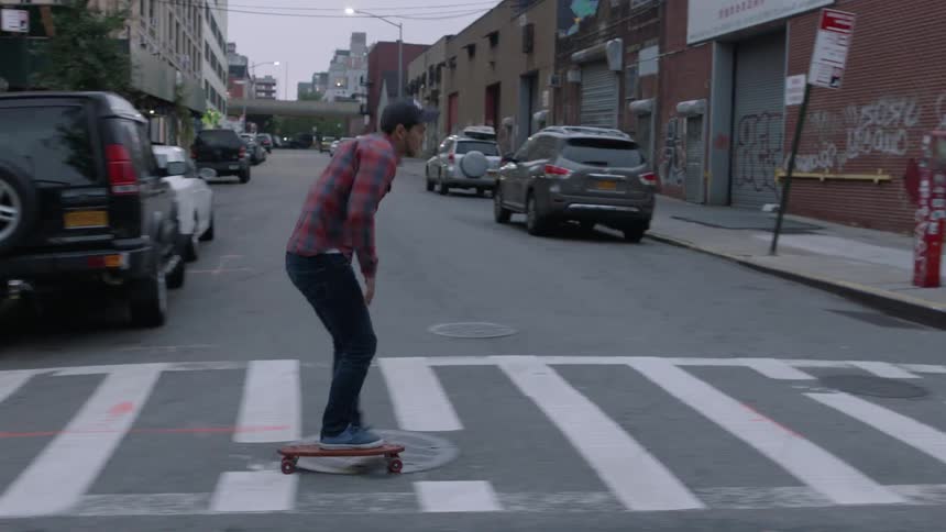 Man riding skateboard down city sidewalk