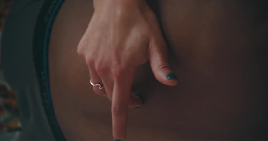 Woman touches mans dreadlocks and back lying on bed