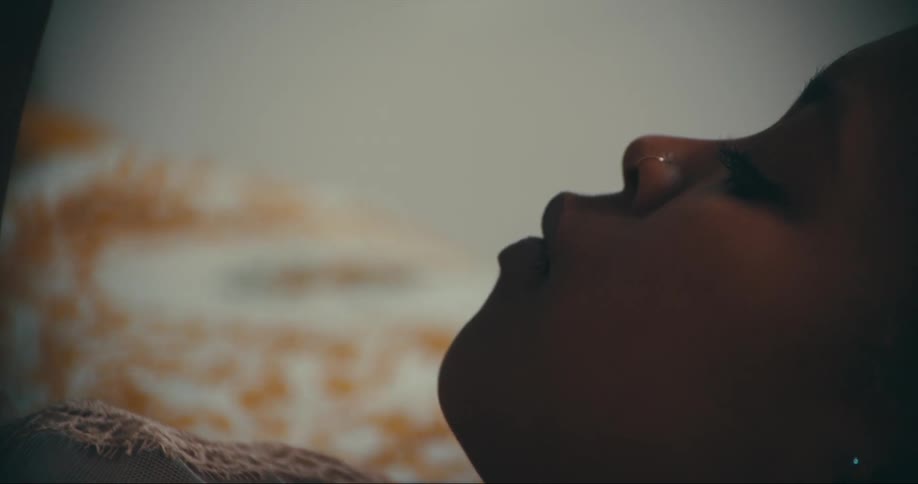 Woman lies on bed with large makeup pallet on her stomach as she eats popcorn from a tub